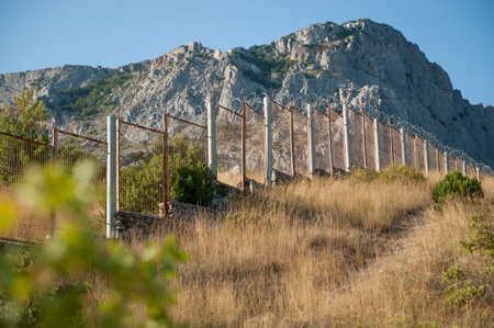 high fencing for illegal immigrants barbed razor wire at USA Mexico state border in rocky mountainsの写真素材