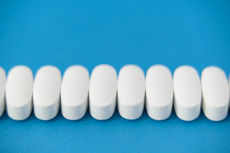 many white health care pills on blue background with copy spaceの写真素材