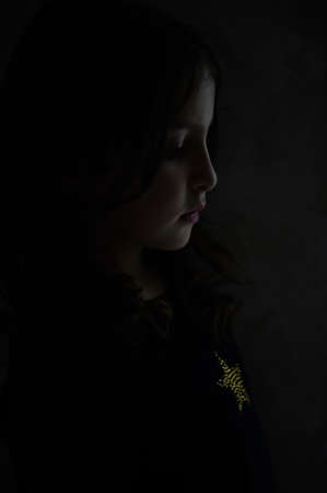 state of mind of beautiful portrait of upset little girl in darkness night moodの写真素材