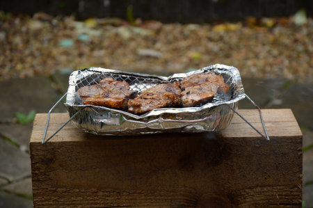 Close-up of foil grill with three sizzling pork steaksの写真素材