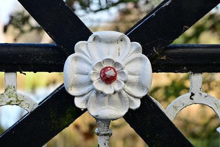 Decorative Metal Flower on Fence with Red Center and Curvesの写真素材