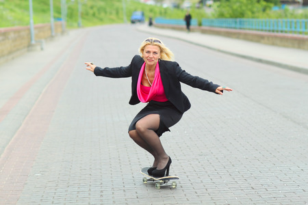 Senior business woman having fun on a skateboard outdoorsの写真素材
