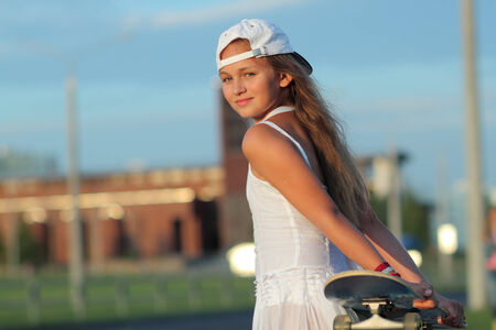 teenage girl riding a skateboard on the evening streetの写真素材