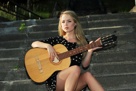 modern hipster girl playing guitar on the street outdoorsの写真素材