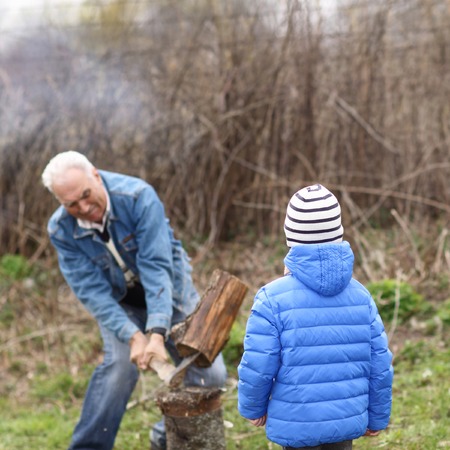 Grandson looks like his grandfather split firewoodの写真素材