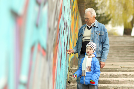 Grandfather and grandson paint graffiti on the wallの写真素材