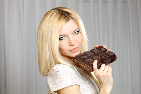 Nice natural cute blonde girl eating a large bar of chocolateの写真素材