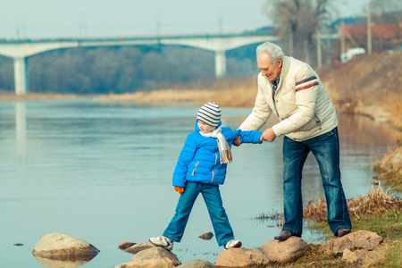 Grandfather and grandson are crossing the river on the stonesの写真素材