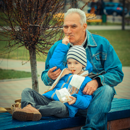 Grandfather and grandson eating fries and indulgeの写真素材