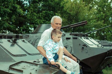 Grandfather and grandson explore military vintage historical transport. Grandfather and grandson at a military armored personnel carrierの写真素材