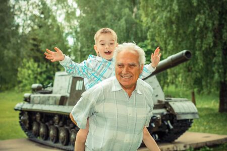 Grandfather and grandson are photographed on a background of vintage tankの写真素材