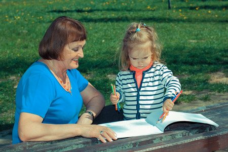 Grandmother and little granddaughter paint outdoors