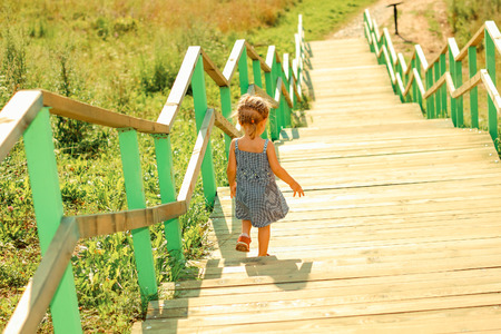 Little girl walking down stairs. View from the back.