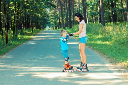 mother and son learn to roller skate. Mom with child having fun on roller skates