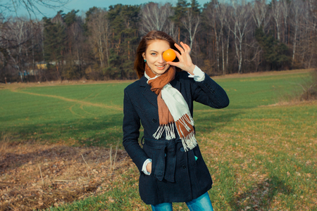 Girl with an orange fruit outdoors. conceptual photo. Fruit, as an example of a healthy diet.の写真素材