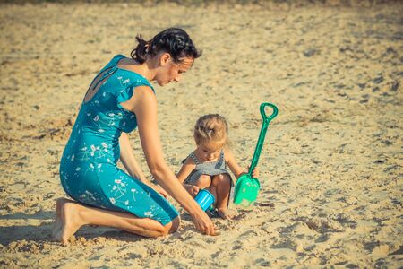 Mother with children playing with sand on beachの写真素材