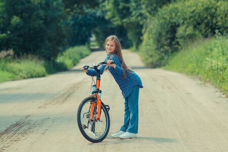 Teenager girl with bicycle in countryside outdoorsの写真素材