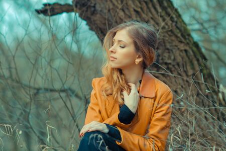 portrait of a beautiful girl in the park in spring. Hipster girl in depressionの写真素材