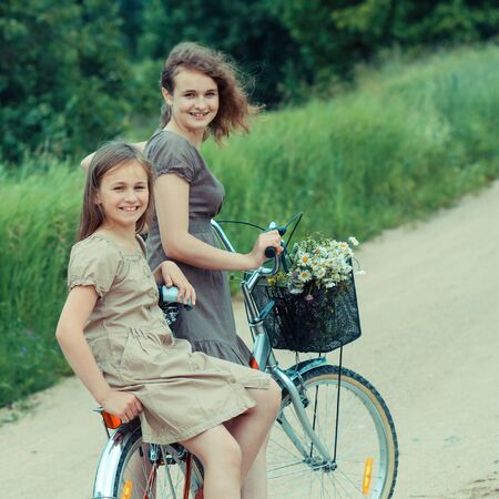 Two hipster girl friends on bicycle having fun. Outdoors, lifestyle. Teenage Girls On Bikeの写真素材