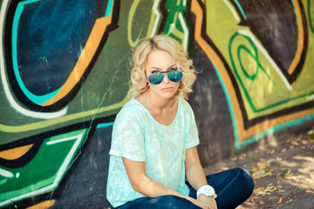 Closeup fashion summer portrait of pretty young sensual woman in sunglasses posing on the background of graffiti. Fashion photo of sexy beautiful Girl. Outdoors lifestyle portraitの写真素材