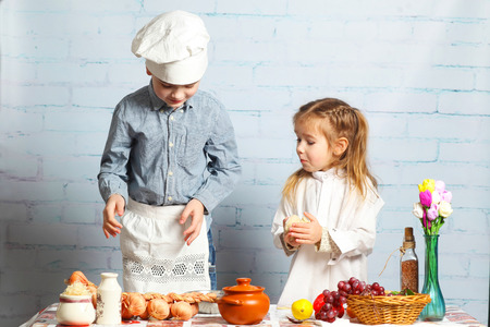 Children chefs. little brother and sister cook in the kitchen. Little boy preparing dough for bread.の写真素材