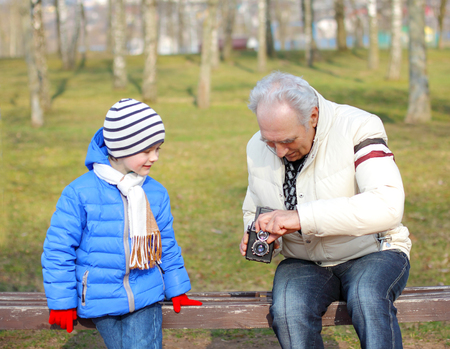 Grandfather with his grandson studying vintage medium format camera. Grandfather shows grandson retro cameraの写真素材