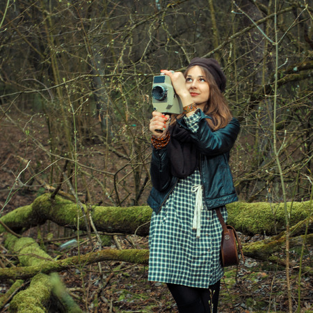 Hipster girl filming in the woods on a vintage movie cameraの写真素材