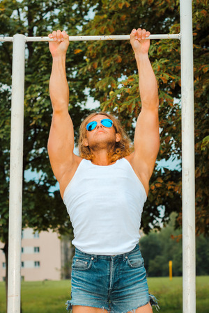 sexy caucasian fit man in sunglasses posing near Sports Bars Outdoors. Strong and confident man...