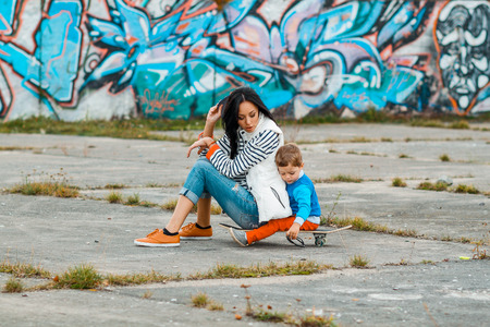 Mother and son on a skateboard. young mother teaches her little boy to ride a skateboardの写真素材
