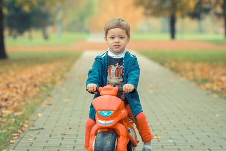 cute little biker on road with motorcycle. Young boy on toy motorcycleの写真素材