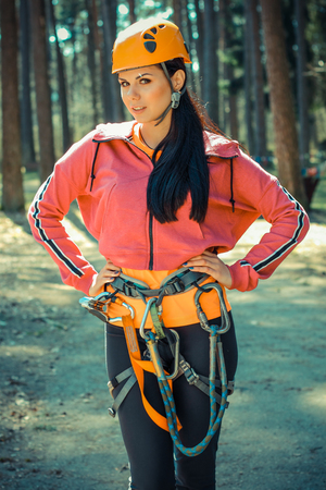 Beautiful girl in the outfit climbing climbs over obstacles between treesの写真素材