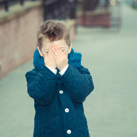 happy little Boy, outdoor. Trendy little boy covers his faceの写真素材