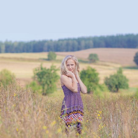 beautiful blonde walks into the field. portrait of a beautiful blonde in a fieldの写真素材