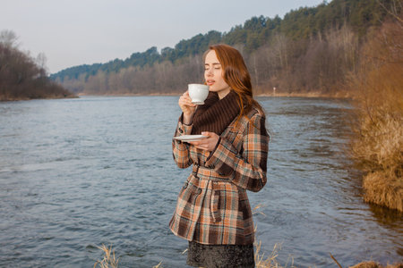 Romantic girl with cup outdoors. Hipster girl drinking tea in the spring in a landscapeの写真素材