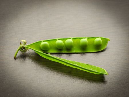 leaf pea pod green peas. Closeup of fresh green peas (Pisum sativum) in a glass jar on a wooden table.  Green peas in a glass dish on a dark background.の写真素材