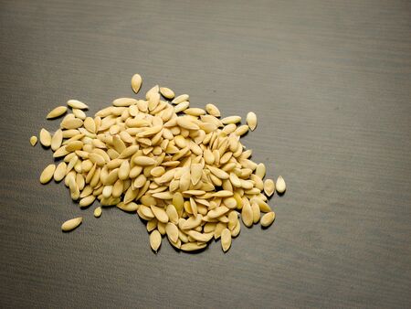 Close of edible dried raw organic seeds of  white melon or cantaloupe on a dark wooden table. Melon seeds with dark background.

の写真素材
