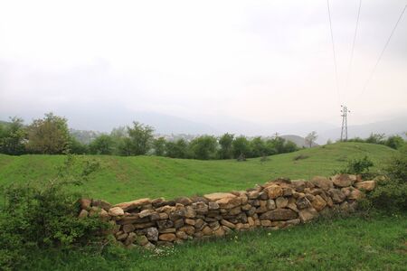 a dry stone wall with stone stile in the beautiful plain of northern Iran  with Cloudy summer, grass and treeの写真素材