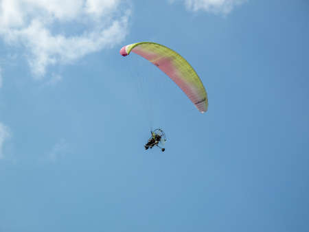 A paraglider flies in the sky under a multi-colored paraglider. paraglider flying under his wing in...