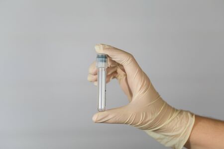 Empty test tube for biomaterial analysis in the hands of a nurse. Clinical virus analysis with precautionary measures.の写真素材