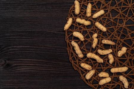 Nuts, shelled peanuts, sprinkle on the table from a linen bag, wooden background. Top view with...