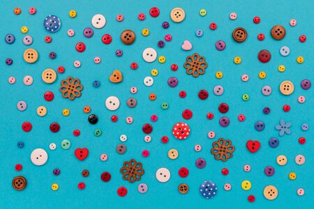 Multicolored buttons are scattered on the table. Top view with copy space, flat lay.