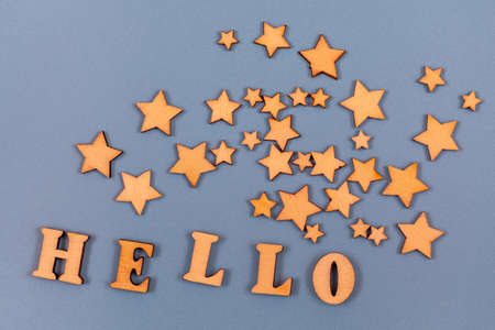 Hello word written in wooden alphabet letters on a gray background. Decorating with wooden stars. Text on the table for design or concept.の写真素材