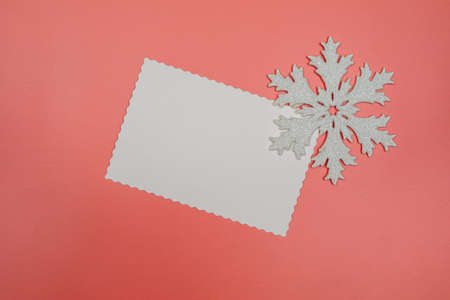 Blank white postcard and snowflake decoration on pink background. Christmas or New Year composition. Flat lay with copy space.の写真素材