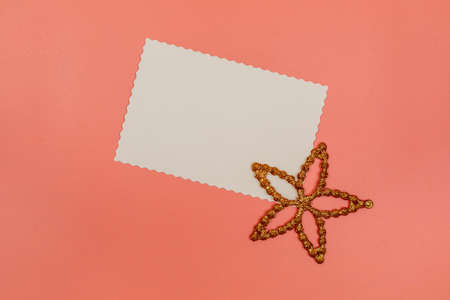 Blank white postcard and decoration star on pink background. Christmas, New Year, Valentines Day, International Womens Day or Mothers Day composition. Flat lay with copy space.の写真素材