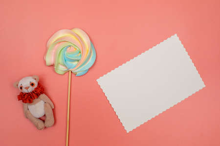 Blank white postcard, rainbow meringue on a stick and teddy bear on a pink background. Christmas, New Year, Valentines Day, International Womens Day or Mothers Day composition.の写真素材