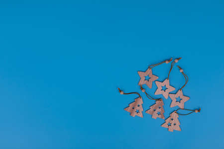 New Year and Christmas wooden toys on blue background. Laser cut wooden Christmas tree and stars figurines. Postcard composition with free space for text. New Year and Christmas concept.の写真素材
