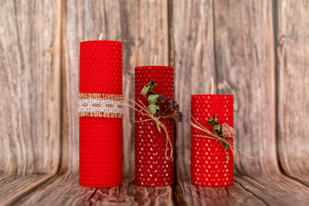 Red honey candles handmade from natural wax on a background of wooden boards. Elements from natural materials. Christmas or New Years composition. Photo for postcards.の写真素材