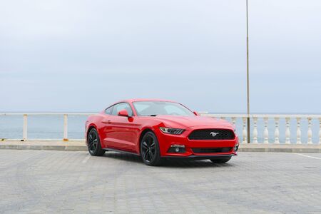 Sports car of red color, against the background of the sea, front view from the sideのeditorial素材