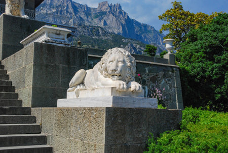 Marble statue of a lion against a background of mountains, vegetation and blue skyの写真素材