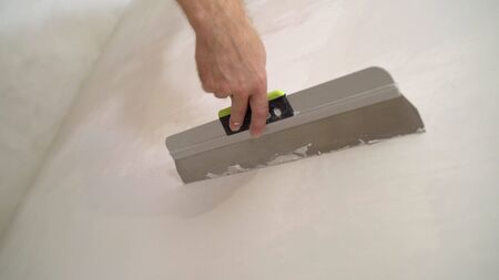 Putting mortar on the wall with a spatula. The builder put mortar on the wall. Plaster walls. Exterior finish.の写真素材